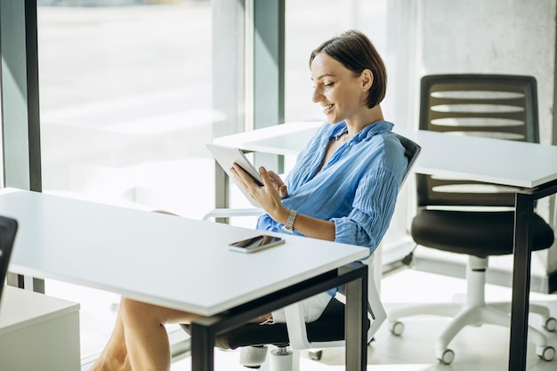 Donna seduta alla scrivania dell'ufficio e utilizzando tablet