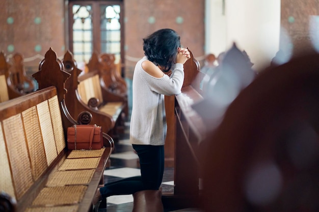 Donna seduta con le mani giunte in chiesa