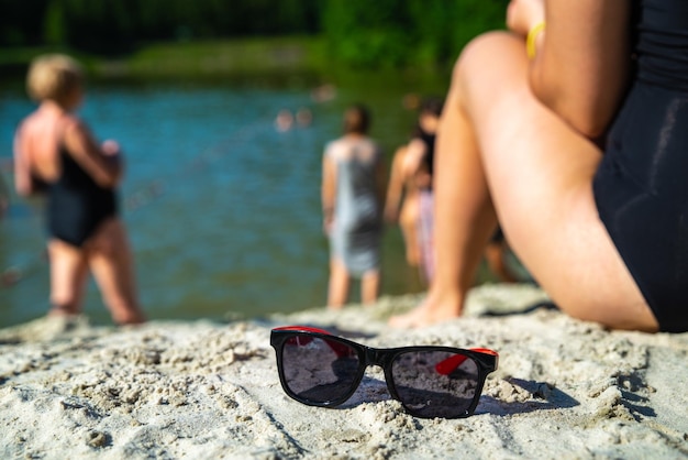 Donna seduta in spiaggia con occhiali da sole vicino all'ora legale