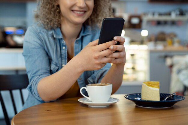 Donna seduta in un caffè e che manda messaggi al telefono.