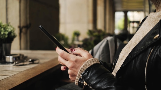 Donna seduta in un caffè usa lo smartphone per fare acquisti online