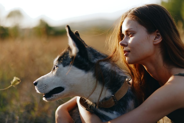 Donna seduta in un campo con un cane bassotto sorridente mentre trascorre del tempo in natura con un cane amico in autunno al tramonto