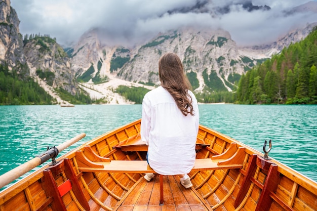 Donna seduta in una grande barca marrone al lago Braies in un giorno nuvoloso in Italia vacanze estive in Europa