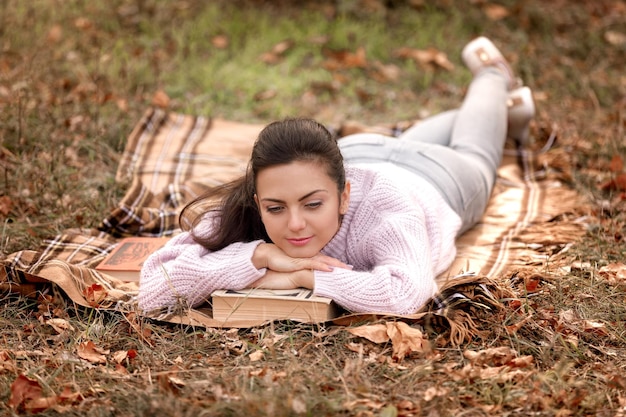 Donna seduta nel parco autunnale e libro di lettura