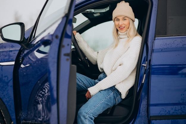 Donna seduta nella sua nuova auto in un parco invernale