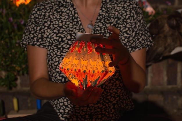 Donna seduta per terra con in mano una lanterna di carta che celebra il giorno delle candele in Colombia