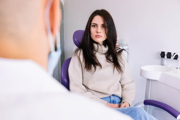 Donna seduta presso l'ufficio del dentista e ascolta il medico sui contro