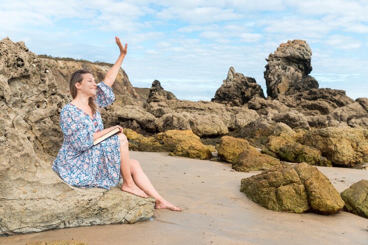 Donna seduta su una roccia che ondeggia sulla spiaggia