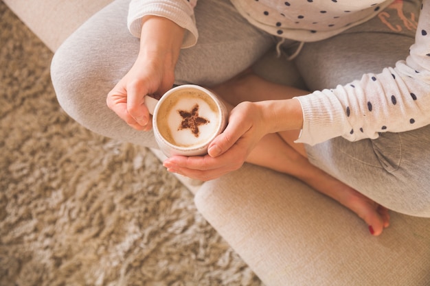 donna seduta sul divano e tenendo una tazza di caffè con una bella stella alla cannella