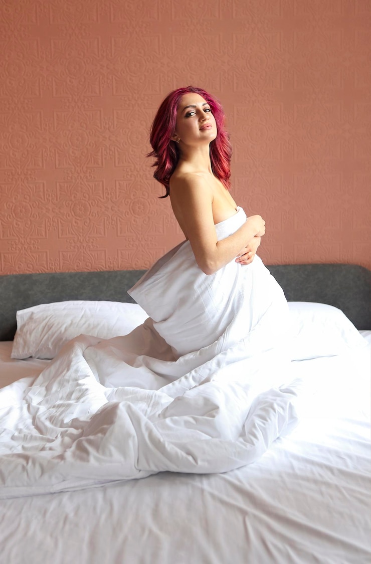 Foto donna seduta sul letto contro il muro a casa