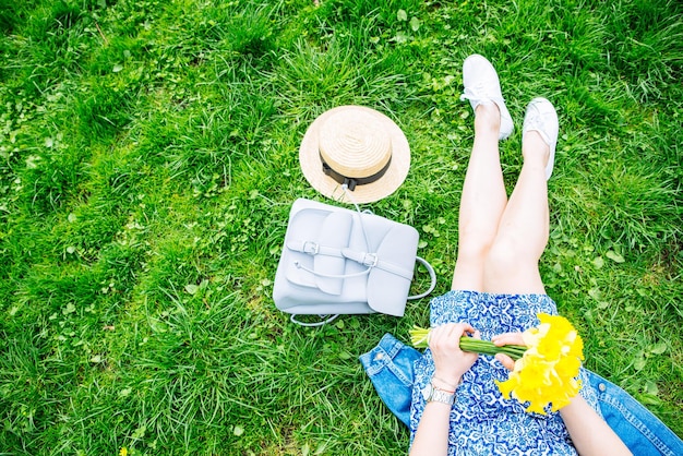 Donna seduta sull'erba nel parco cittadino con fiori gialli