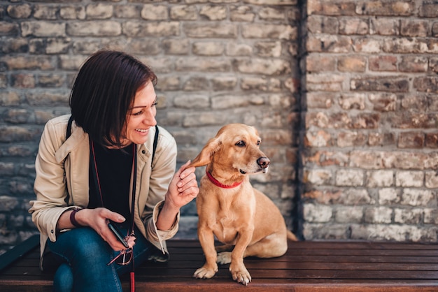 Donna seduta sulla panchina e coccole il suo cane