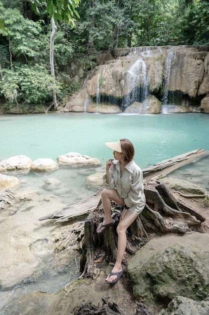 Donna seduta sulla pietra a Erawan cascata al Parco Nazionale di Kanchanaburi Thailandia