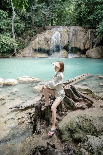 Donna seduta sulla pietra a Erawan cascata al Parco Nazionale di Kanchanaburi Thailandia