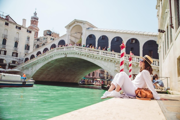 Donna seduta vicino al ponte di rialto a venezia italia guardando il canal grande con le gondole