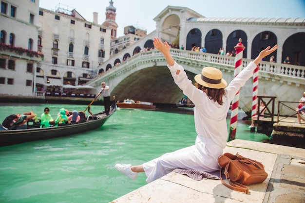 Donna seduta vicino al ponte di rialto a venezia italia guardando il canal grande con lo spazio della copia dell'ora legale delle gondole