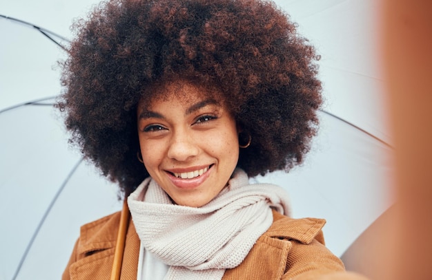 Donna selfie primo piano e ombrello in acqua piovana o pioviggine in ritratto felicità e sorriso Capelli donna nera o bellezza afro con ombrellone per protezione dagli elementi clima o tempesta mentre felice