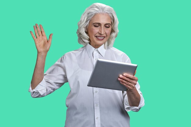 Donna senior allegra che fluttua con la mano mentre guarda la donna di affari maturi del tablet pc che ha video