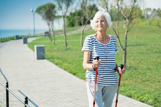 Donna senior che cammina con i pali