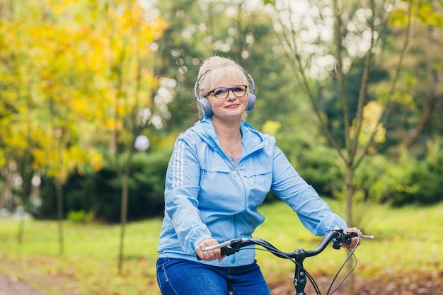 donna senior che cammina nel parco con una bicicletta