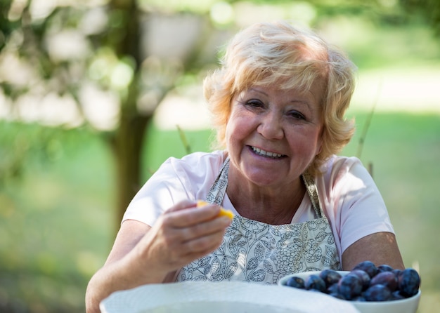 Donna senior che mangia albicocca in giardino