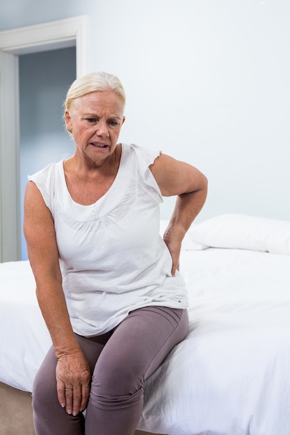 Donna senior che soffre di mal di schiena mentre era seduto in camera da letto