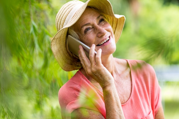 Donna senior che utilizza telefono nell'iarda