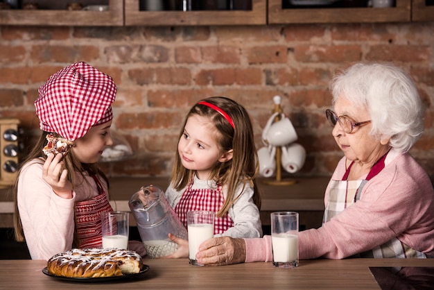 Donna senior con i nipoti che sorridono e che assaggiano torta