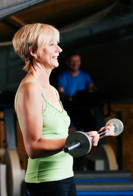 Donna senior con il bilanciere in palestra