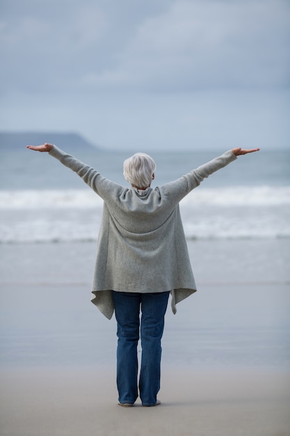 Donna senior con la condizione stesa di armi sulla spiaggia