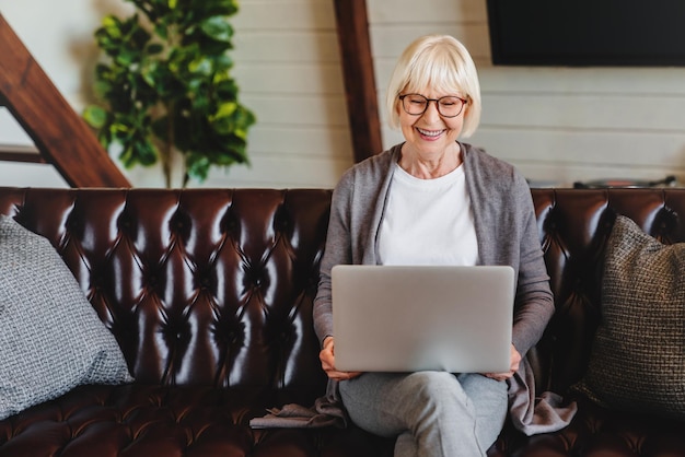 Donna senior felice che utilizza il computer portatile a casa