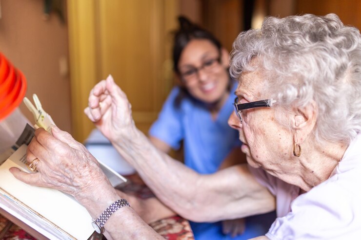Donna senior felice con il suo badante a casa che legge un libro