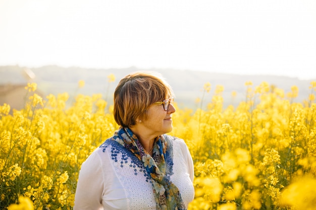 Donna senior in un campo di fiori gialli