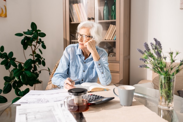 Donna senior pensierosa che conta le tasse