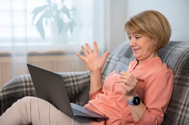 donna senior sorpresa esclama con laptop, carta di credito in mano per lo shopping su Internet