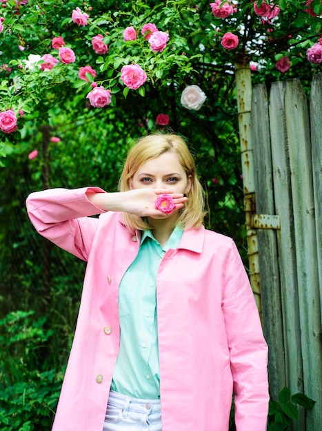 Donna sensuale al parco con rose rosa. Bella ragazza in giardino fiorito.