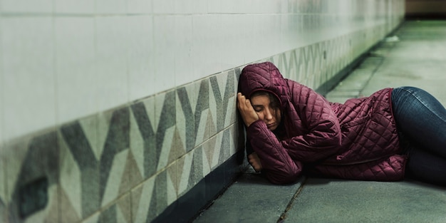 Donna senzatetto che dorme sul pavimento