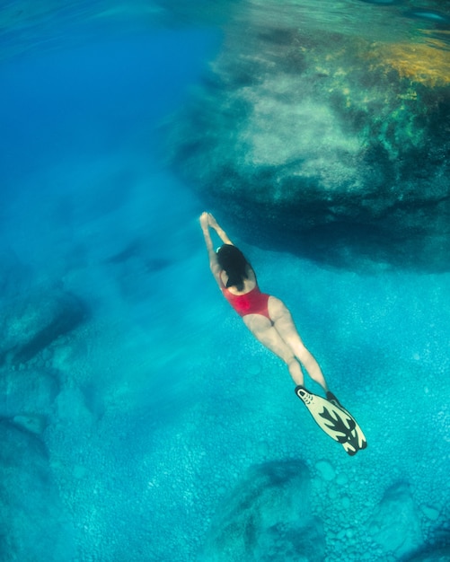 Donna sexy che nuota sott'acqua in maschera subacquea con le vacanze estive di pinne
