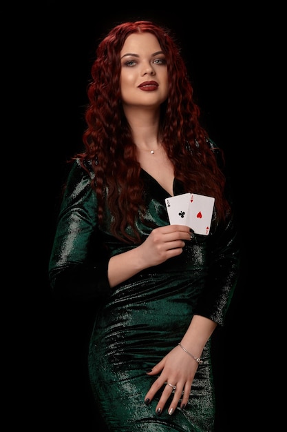 Donna sexy dai capelli rossi in posa con carte da gioco in mano, su sfondo nero