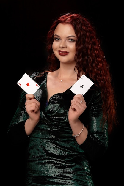 Donna sexy dai capelli rossi in posa con carte da gioco in mano, su sfondo nero