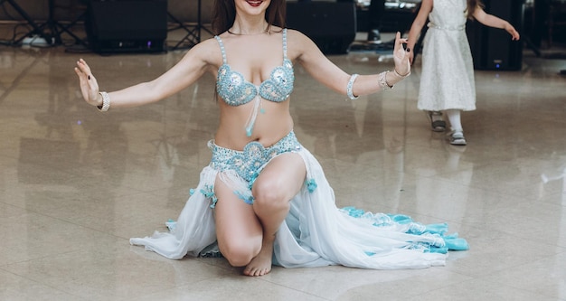 Donna sexy di danza orientale in costume blu che esegue danza orientale danzatrice del ventre bella donna che balla al ricevimento di nozze nel ristorante