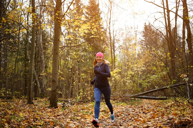 Donna snella che corre nel parco in autunno