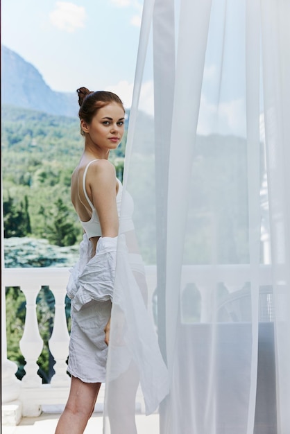 Donna snella si trova su una terrazza balcone in biancheria luce del sole bella vista Stile di vita