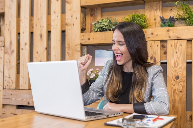 Donna soddisfatta che urla con la bocca aperta mentre lavora online