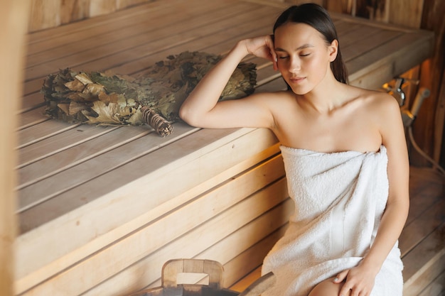 Donna soddisfatta con gli occhi chiusi che si rilassa nella sauna