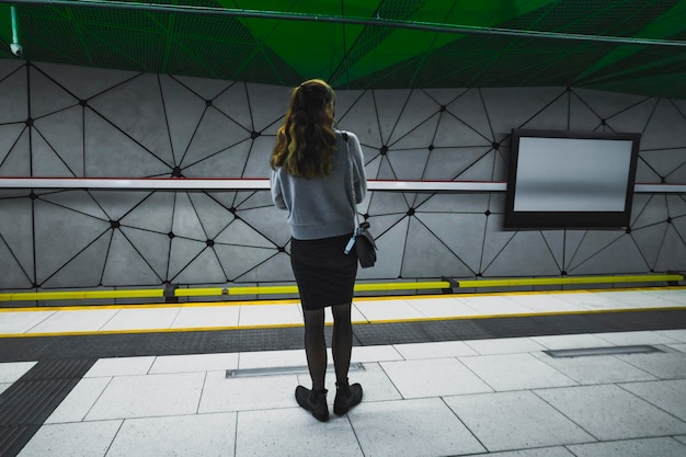 Donna sola al binario della stazione della metropolitana