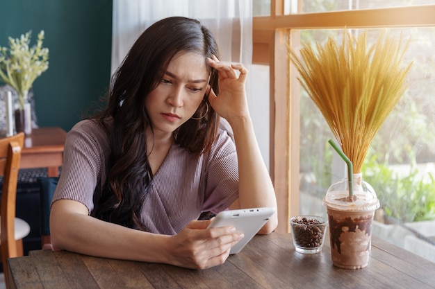 Donna sollecitata che utilizza compressa nel caffè