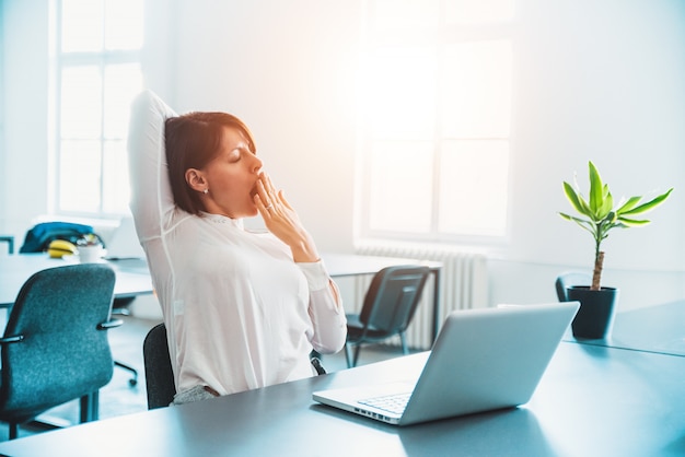 Donna sonnolenta stanca che sbadiglia, lavorando alla scrivania.