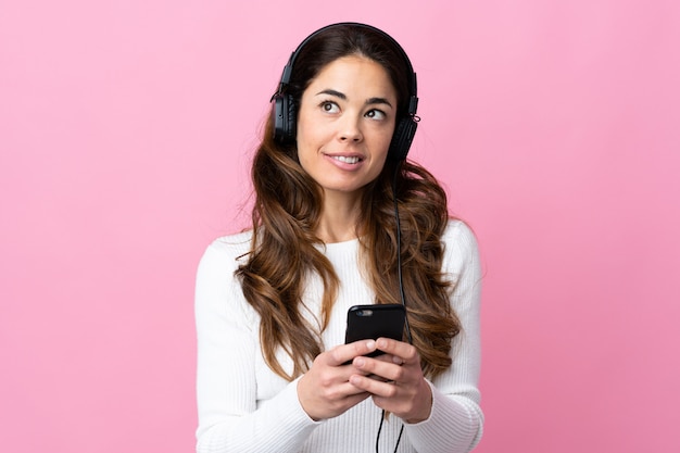 Donna sopra musica d'ascolto rosa isolata con un cellulare e un pensiero