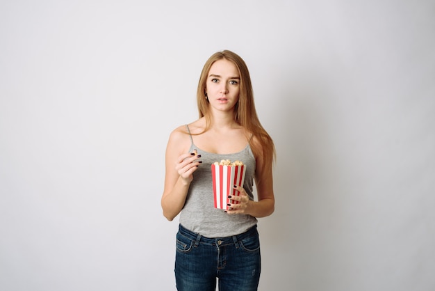 Donna sorprendente che mangia popcorn. Ragazza che tiene grande scatola a strisce con porzione di cinema di pop corn. Wow